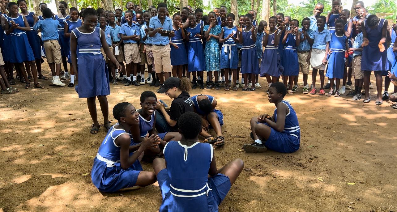 School children sitting on the ground in their uniforms
